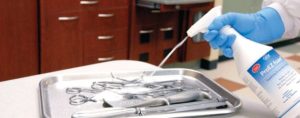 Healthcare worker spraying surgical instruments for cleaning