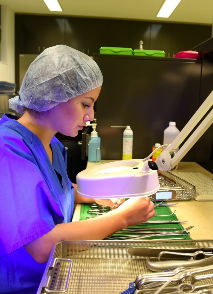 hospital staff inspecting surgical instruments using a magnifying light.