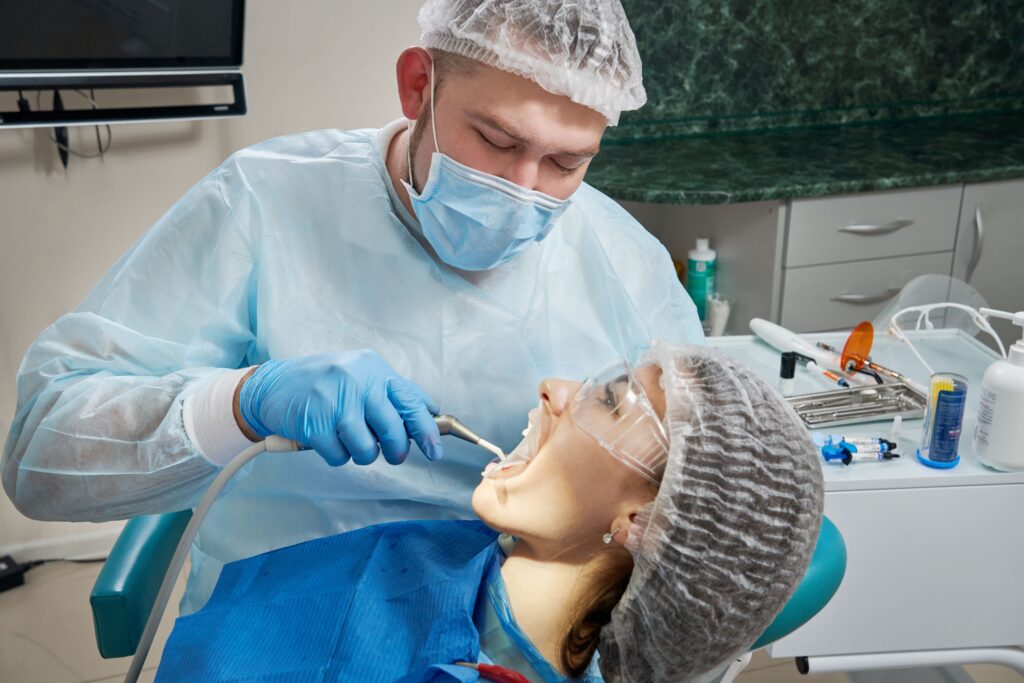 Dentist using water hose to rinse patient's mouth.