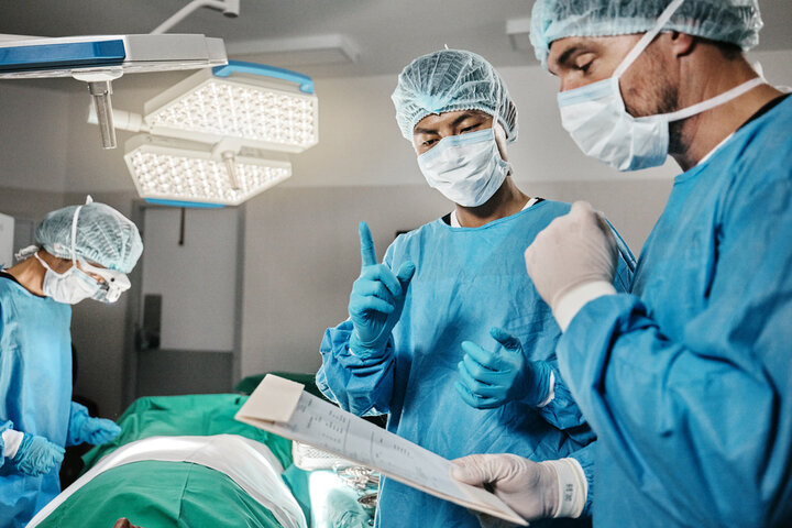 Surgeons reviewing procedural checklist before operating on patient.